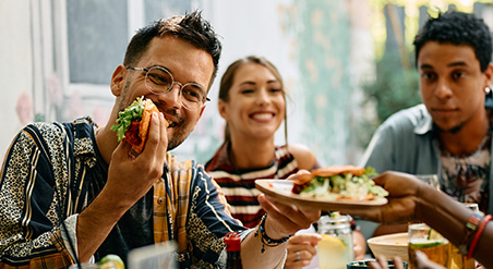 Diverse students sharing a meal of tacos and passing plates at a table.