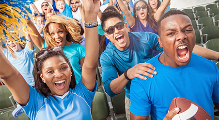 Group of diverse students cheering in the crowd at a football game.