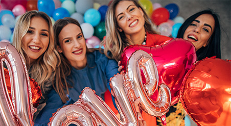 Group of four female students pose with pink and red balloons that say love.