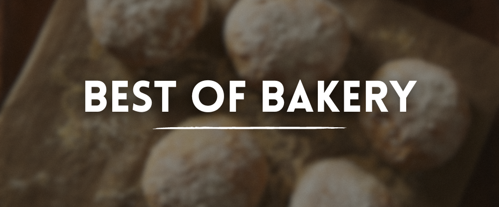 Blurred fresh bread buns with flour topping on a wooden cutting board with white text “Best Of Bakery” overlay.