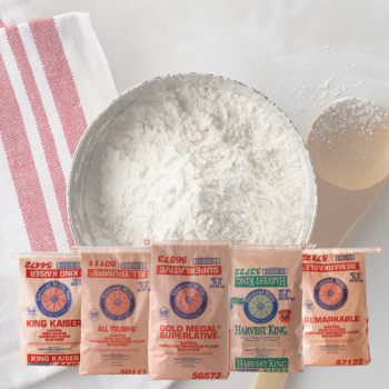 Blurred fresh bread buns with flour topping on a wooden cutting board with white text “Best Of Bakery” overlay.