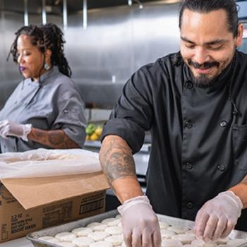 Cooks working in a foodservice kitchen to prepare Pillsbury biscuits for the menu