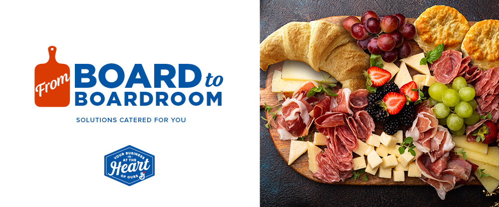 From board to boardroom text in blue and white. Cutting board icon in orange. Image of charcuterie on wooden board. Assortment includes salted meats, croissants, biscuits, cheese, grapes, and berries.
