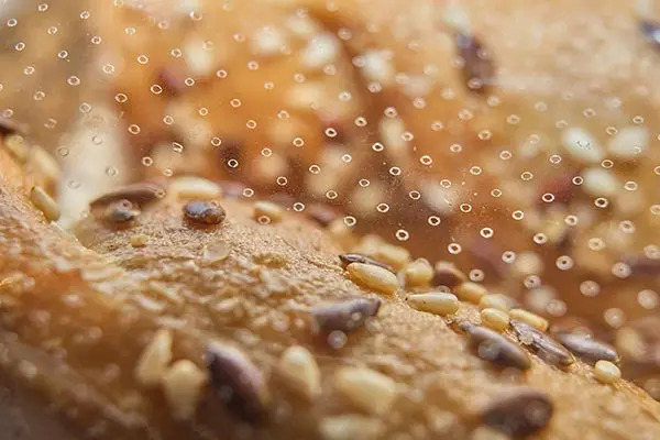 Close-up of a loaf of bread topped with various seeds, including sesame seeds, showcasing its texture and detail.