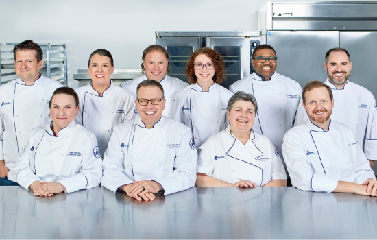 Ten chefs in white chef coats posed before a professional chef’s counter Celebrating success: Inspiring stories and our latest Biskies winners!