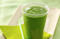 green smoothie on small tray with a green napkin and straw